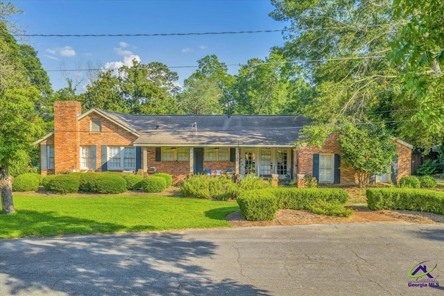 709 Evergreen St, Perry, GA 31069 - ranch-style house with brick siding, a front yard, a chimney, and covered porch