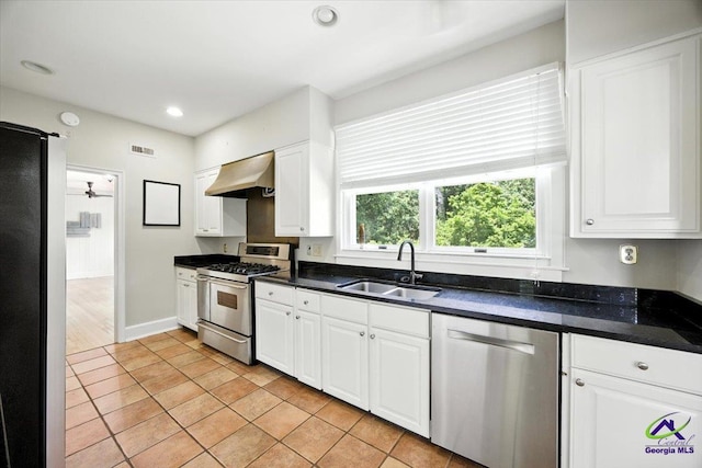 458 Pierce Ave, Macon, GA 31204 - kitchen with appliances with stainless steel finishes, wall chimney exhaust hood, dark countertops, white cabinetry, and light tile patterned floors