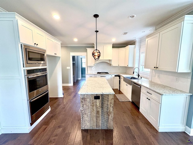 300 Stacy Ln, Warner Robins, GA 31088 - kitchen featuring stainless steel appliances, ornamental molding, a center island, tasteful backsplash, and light stone counters