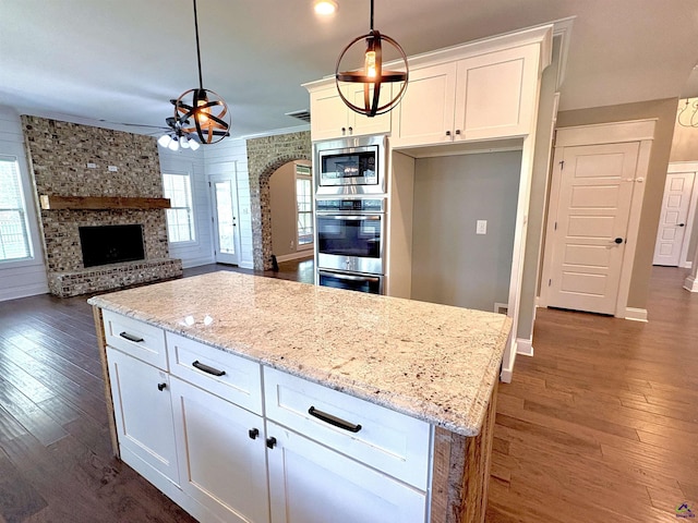 300 Stacy Ln, Warner Robins, GA 31088 - kitchen with stainless steel microwave, healthy amount of natural light, dark wood-style floors, and white cabinetry