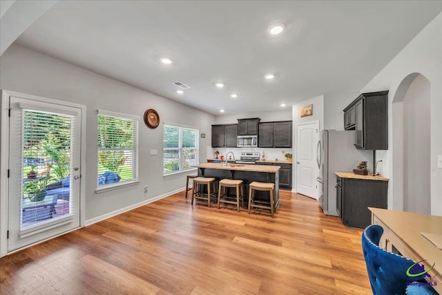 215TYNDALLWAY Tyndall Way, Perry, GA 31069 - kitchen with stainless steel appliances, arched walkways, light wood-style flooring, a kitchen island with sink, and a breakfast bar area
