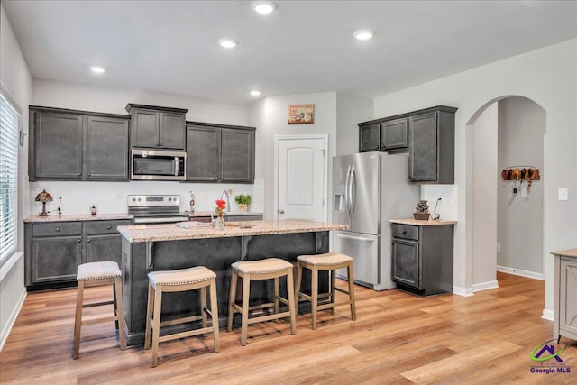 215TYNDALLWAY Tyndall Way, Perry, GA 31069 - kitchen with appliances with stainless steel finishes, arched walkways, a center island with sink, a breakfast bar area, and decorative backsplash