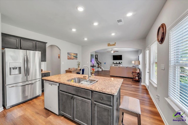 215TYNDALLWAY Tyndall Way, Perry, GA 31069 - kitchen with stainless steel appliances, arched walkways, open floor plan, a kitchen island with sink, and light stone countertops
