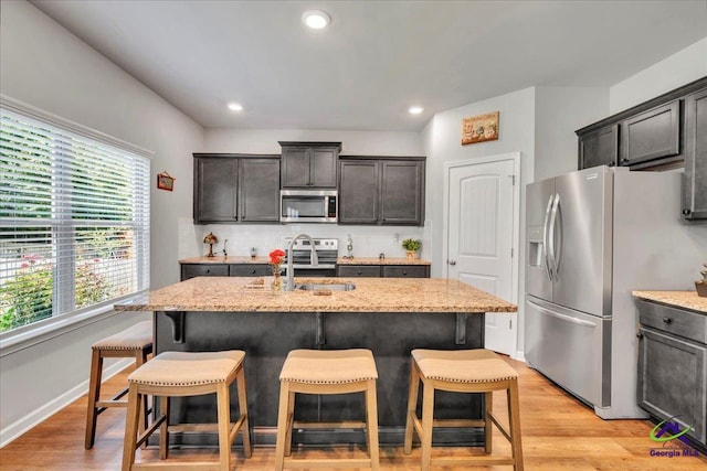 215TYNDALLWAY Tyndall Way, Perry, GA 31069 - kitchen with appliances with stainless steel finishes, light stone counters, a kitchen bar, an island with sink, and decorative backsplash