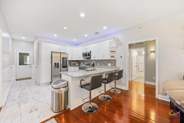 129 Sugarloaf Dr, Macon, GA 31204 - kitchen featuring stainless steel appliances, a peninsula, open shelves, white cabinetry, and light stone countertops