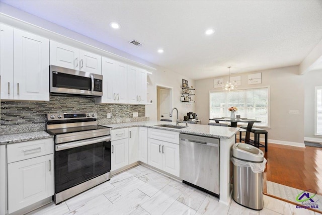 129 Sugarloaf Dr, Macon, GA 31204 - kitchen featuring stainless steel appliances, a chandelier, a peninsula, backsplash, and white cabinets