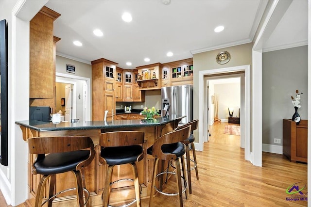 612 Remington Dr, Macon, GA 31210 - kitchen with a peninsula, crown molding, stainless steel refrigerator with ice dispenser, light wood-type flooring, and a kitchen bar