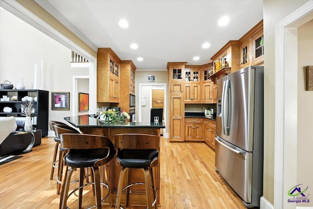 612 Remington Dr, Macon, GA 31210 - kitchen featuring stainless steel refrigerator with ice dispenser, a breakfast bar, dark countertops, a peninsula, and light wood finished floors