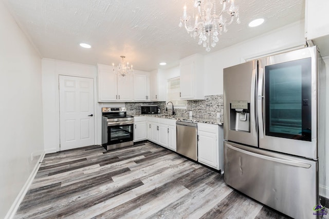 4354 Pio Nono Ave, Macon, GA 31206 - kitchen featuring appliances with stainless steel finishes, a chandelier, wood finished floors, white cabinets, and tasteful backsplash