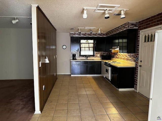 108 Virginia Dr, Warner Robins, GA 31093 - kitchen with electric stove, light countertops, dark cabinetry, light tile patterned floors, and a textured ceiling
