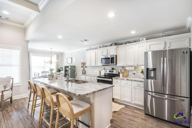 306 Gibson Cir, Kathleen, GA 31047 - kitchen featuring appliances with stainless steel finishes, crown molding, white cabinets, a kitchen island with sink, and a breakfast bar