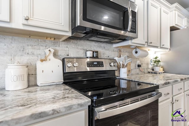 306 Gibson Cir, Kathleen, GA 31047 - kitchen featuring appliances with stainless steel finishes, white cabinetry, decorative backsplash, and light stone counters