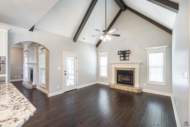 301 Vinings Place Dr, Warner Robins, GA 31088 - unfurnished living room featuring a tiled fireplace, arched walkways, a ceiling fan, beamed ceiling, and dark wood-type flooring
