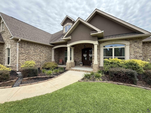 240 Woodlands Blvd, Kathleen, GA 31047 - view of front facade with covered porch, roof with shingles, brick siding, a front yard, and stucco siding