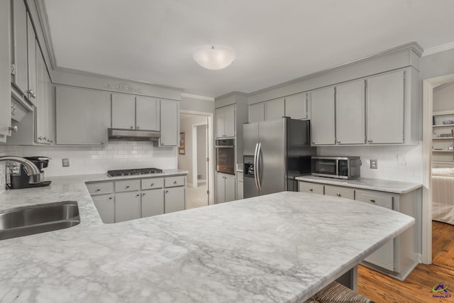 4871 Oxford Rd, Macon, GA 31210 - kitchen with appliances with stainless steel finishes, crown molding, gray cabinetry, under cabinet range hood, and tasteful backsplash