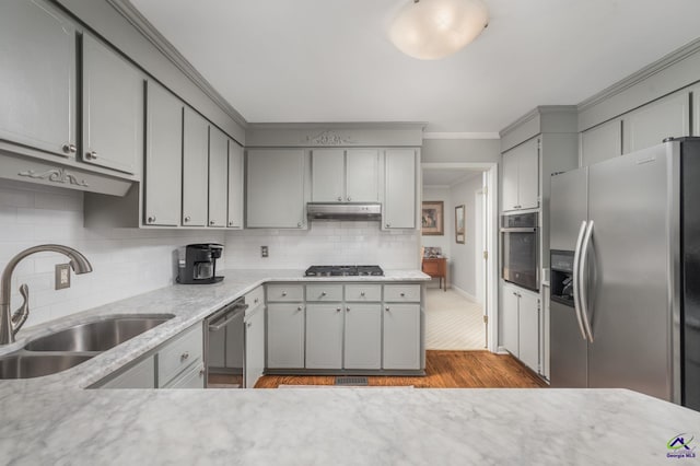 4871 Oxford Rd, Macon, GA 31210 - kitchen featuring appliances with stainless steel finishes, gray cabinetry, wood finished floors, under cabinet range hood, and decorative backsplash