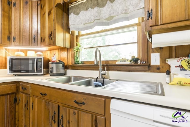 2740 Riverview Rd, Macon, GA 31204 - kitchen with stainless steel microwave, dishwasher, light countertops, brown cabinetry, and wood walls