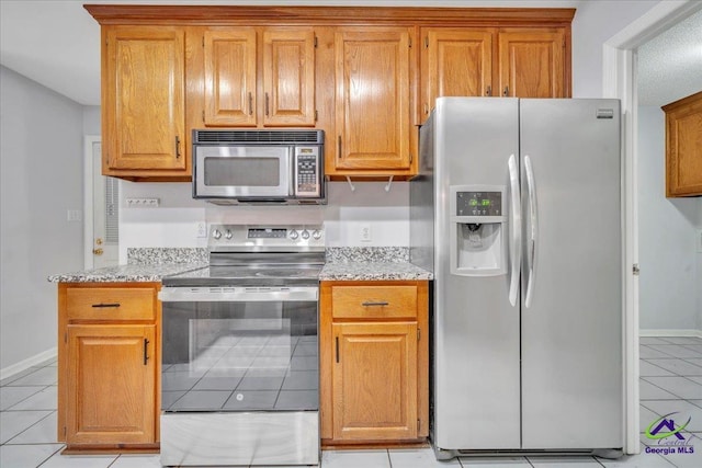 105 International Blvd, Warner Robins, GA 31088 - kitchen with appliances with stainless steel finishes, light tile patterned flooring, light stone counters, and brown cabinets