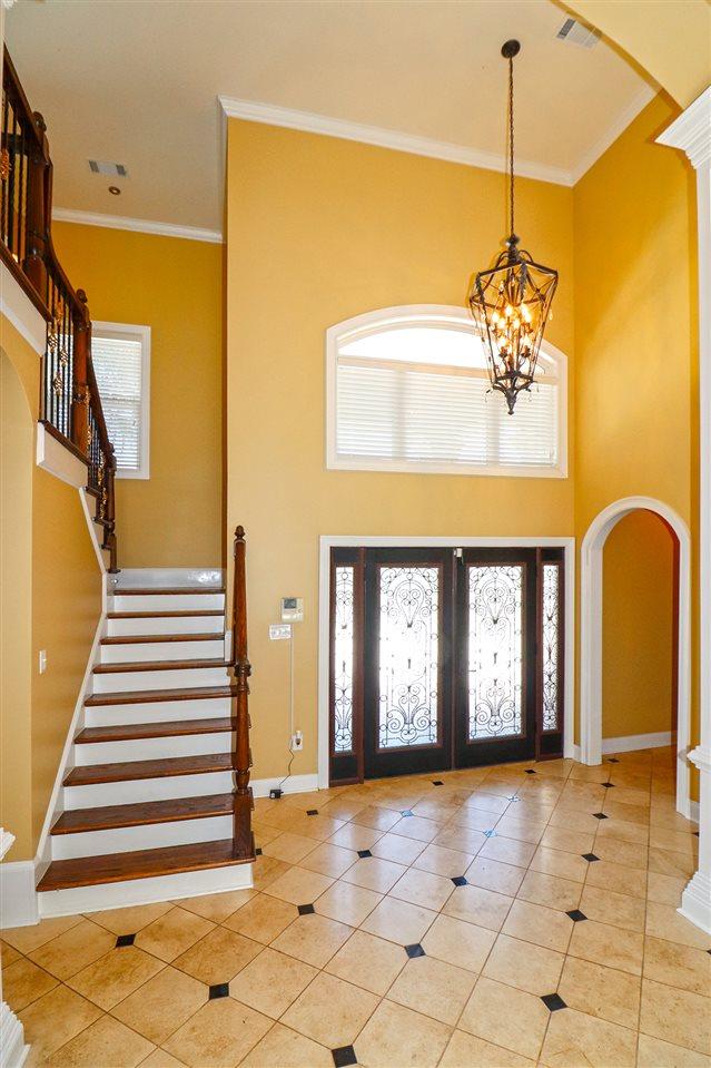 tiled entryway with an inviting chandelier, a healthy amount of sunlight, a high ceiling, and french doors