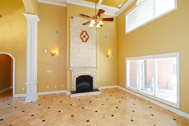 unfurnished living room featuring a large fireplace, decorative columns, light tile flooring, and ceiling fan