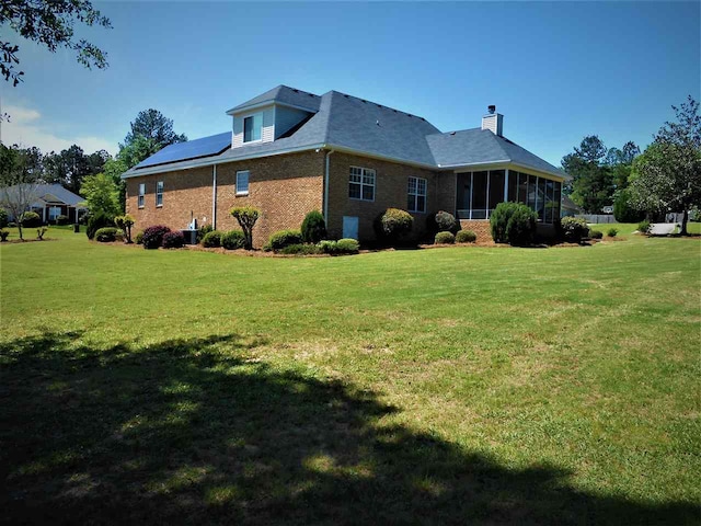 back of house featuring central AC, a sunroom, and a lawn