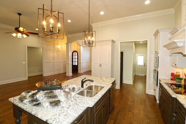 kitchen with light stone countertops, stainless steel appliances, dark brown cabinets, and sink