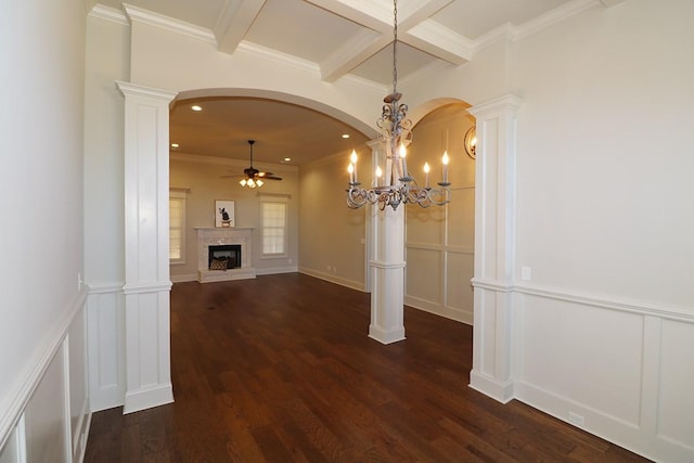 hallway with an inviting chandelier, dark wood-type flooring, and ornate columns