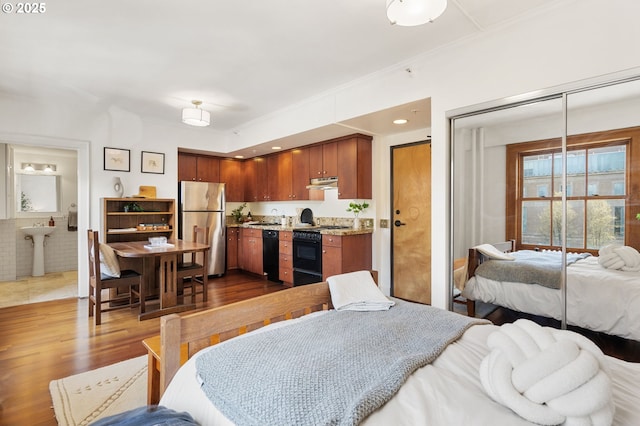 kitchen featuring black appliances, ornamental molding, under cabinet range hood, open floor plan, and dark wood finished floors