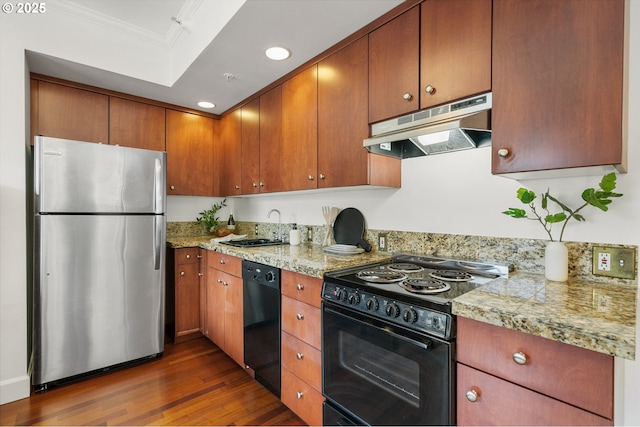 kitchen with black appliances, under cabinet range hood, a sink, dark wood finished floors, and crown molding