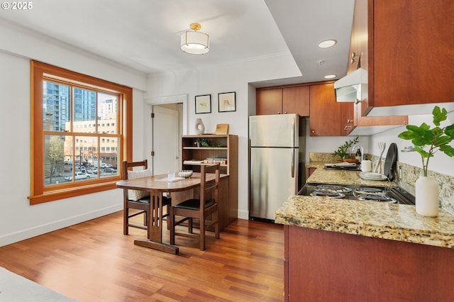 kitchen with a sink, light wood-type flooring, range hood, and freestanding refrigerator
