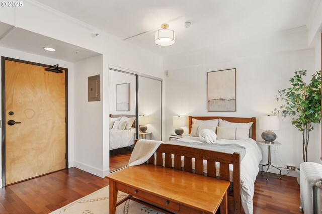 bedroom featuring electric panel, a closet, wood finished floors, and ornamental molding