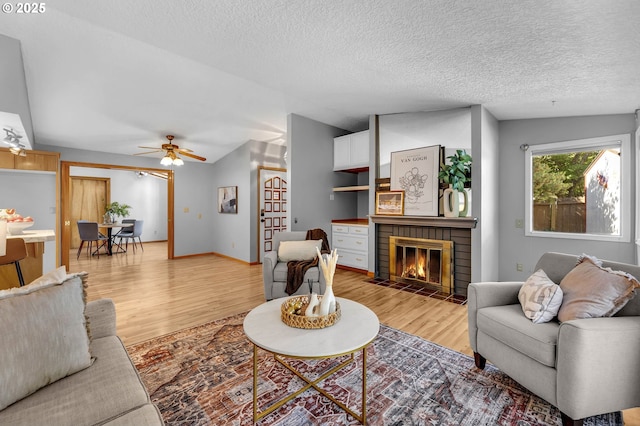 602 SE 130th Ct, Vancouver, WA 98683 - living room featuring light wood finished floors, a fireplace, a textured ceiling, lofted ceiling, and a ceiling fan