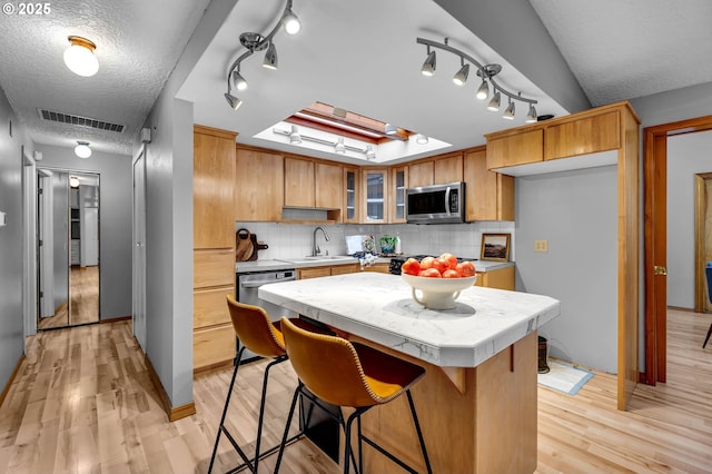602 SE 130th Ct, Vancouver, WA 98683 - kitchen featuring stainless steel appliances, rail lighting, light wood finished floors, glass insert cabinets, and a textured ceiling