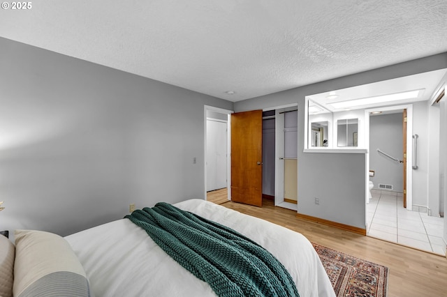 602 SE 130th Ct, Vancouver, WA 98683 - bedroom with wood finished floors, a textured ceiling, baseboards, and ensuite bathroom
