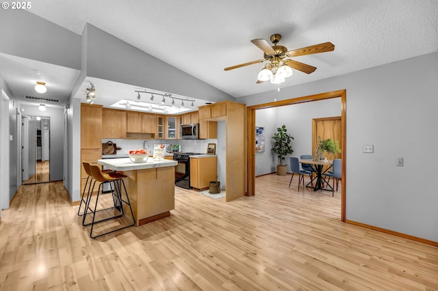 602 SE 130th Ct, Vancouver, WA 98683 - kitchen with stainless steel microwave, light wood-style floors, lofted ceiling, a center island, and a kitchen breakfast bar