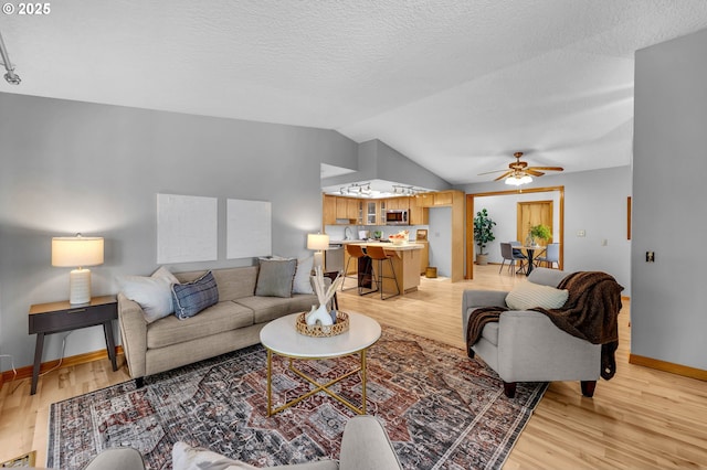 602 SE 130th Ct, Vancouver, WA 98683 - living room featuring light wood finished floors, lofted ceiling, ceiling fan, baseboards, and a textured ceiling