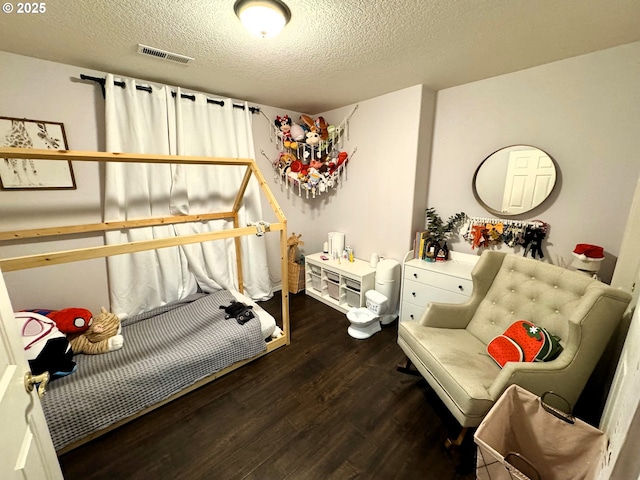 bedroom with visible vents, a textured ceiling, and wood finished floors