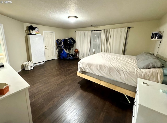 bedroom with a textured ceiling and dark wood finished floors