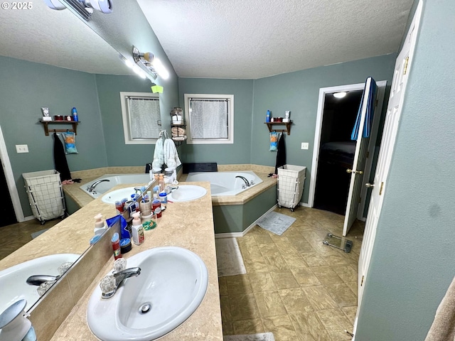 full bathroom with a bath, double vanity, a textured ceiling, and a sink