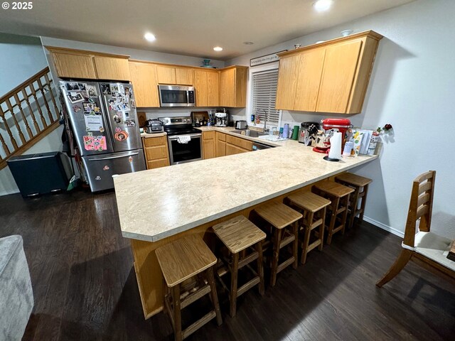 kitchen with stainless steel appliances, a peninsula, dark wood finished floors, and light countertops