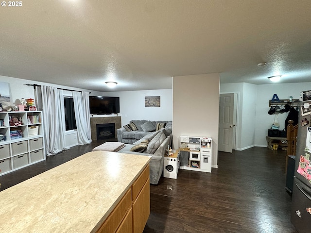 kitchen featuring a textured ceiling, dark wood-type flooring, brown cabinetry, and a tile fireplace