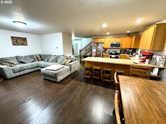 living area with dark wood-style floors, stairway, a textured ceiling, and recessed lighting