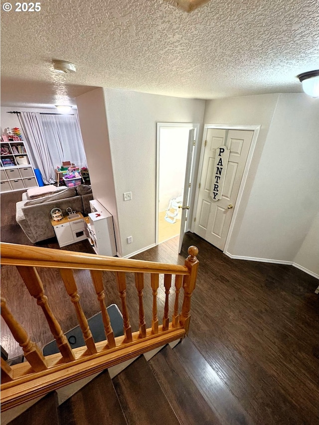 entrance foyer featuring a textured ceiling, baseboards, and wood finished floors