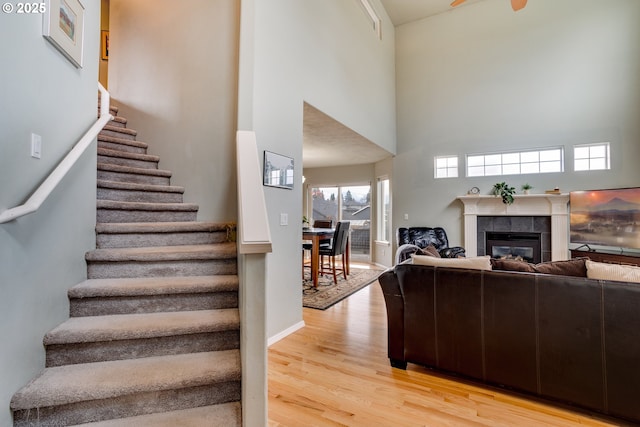 living room featuring a tile fireplace, a high ceiling, and light wood-type flooring