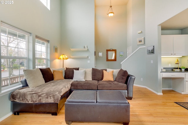 living room with a towering ceiling and light wood-type flooring