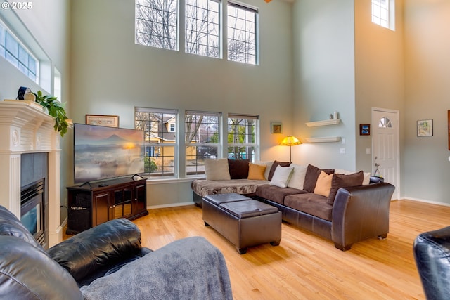 living room with a wealth of natural light, light hardwood / wood-style flooring, and a high ceiling