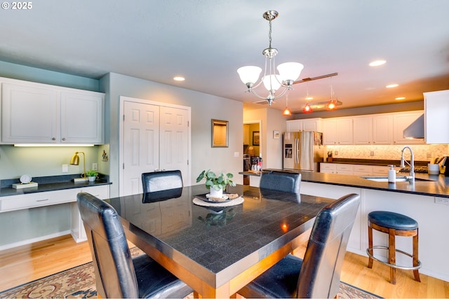 dining space with sink, a notable chandelier, and light hardwood / wood-style floors