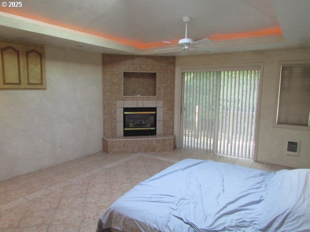 10285 S Rosewood Way, Molalla, OR 97038 - bedroom featuring a raised ceiling, light tile patterned floors, a tiled fireplace, and ceiling fan
