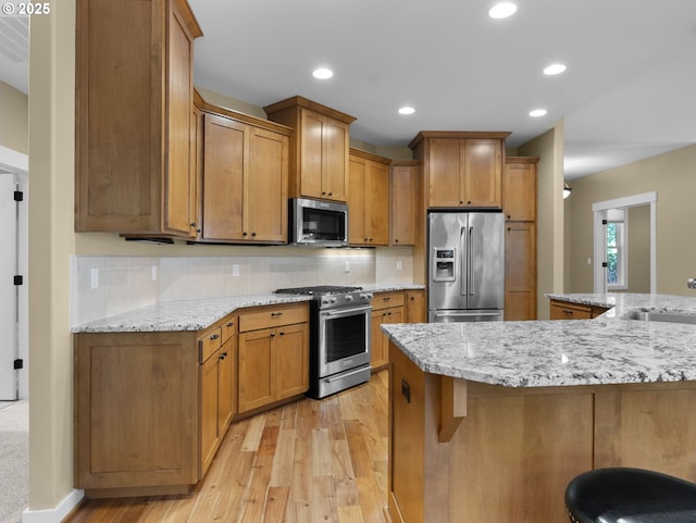 64911 E Mountain Meadow Ln, Rhododendron, OR 97049 - kitchen featuring stainless steel appliances, light wood-type flooring, decorative backsplash, brown cabinets, and a sink