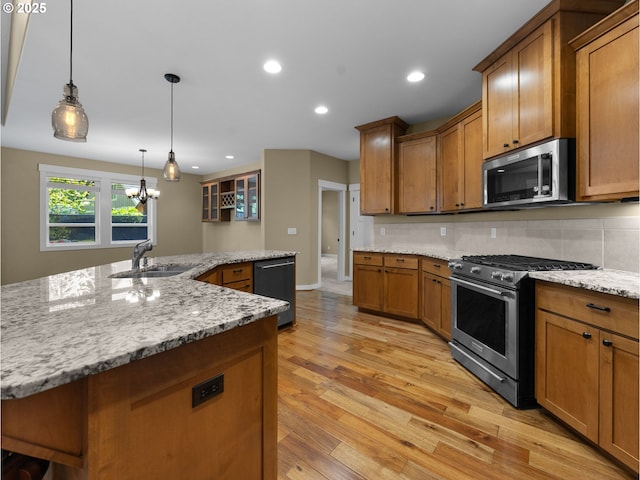 64911 E Mountain Meadow Ln, Rhododendron, OR 97049 - kitchen with appliances with stainless steel finishes, a sink, brown cabinetry, light wood-style floors, and a chandelier